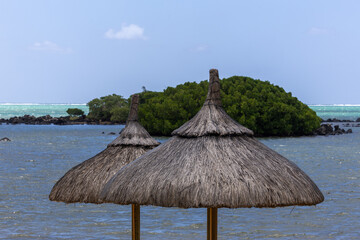 Sun umbrella and beach beds on tropical coastline, in Mauritius