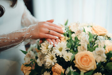 Bride's hands with wedding ring on bouquet.