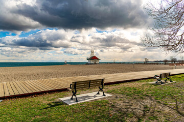 looking out to the horizon past park benches and a wooden boardwalk to a classic wooden lifeguard...