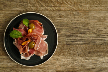 Prosciutto ham plate with olives on wooden table