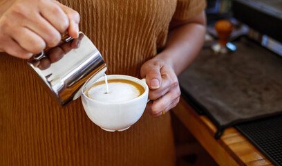 Barista pouring milk into coffee making a cappuccino. Barista making cappuccino,Professional...