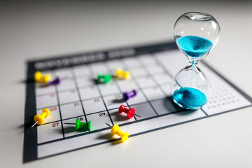 Hourglass on calendar with thumbtacks - 764803315