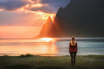 Woman traveling in Norway walking alone on sunset Ersfjord beach harmony with nature healthy...