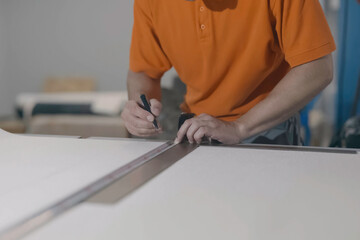 A man measures with tape measure and makes marks with a pencil.