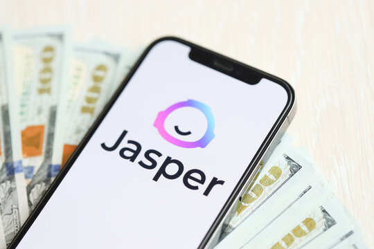 KYIV, UKRAINE - MARCH 17, 2024 Jasper logo on iPhone display screen with many hundred dollar bills. Artificial Intelligence engine