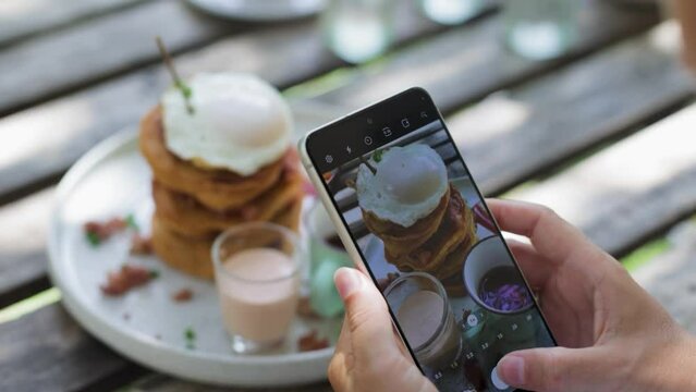taking pictures of a stack of pancakes with a poached egg.