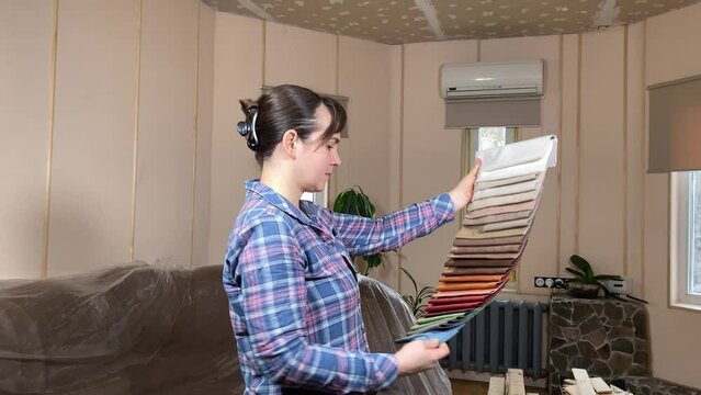 A beautiful woman engages in home improvement, planning preparing for renovation on backdrop of construction materials indoors. Reconstruction, DIY concept. Handywoman chooses wall paint color palette