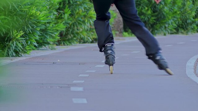 young man roller-skating on a special path in the summer city park