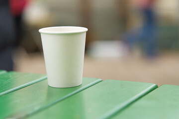 Paper cup on a turquoise outdoor table, cropped image