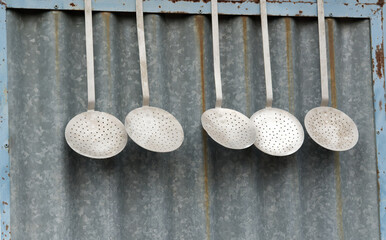 old slotted spoon hanging on a corrugated iron wall, old kitchen spoons, nostalgic