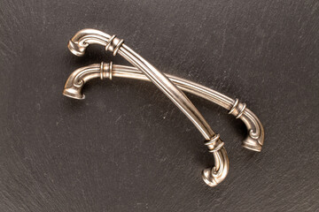 Two metal drawer handles on slate stone, furniture accessories, macro, top view.