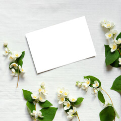 Jasmine flowers with blank empty card on light linen background.  Birthday, Mother's Day. Copy space. Creative spring greeting card
