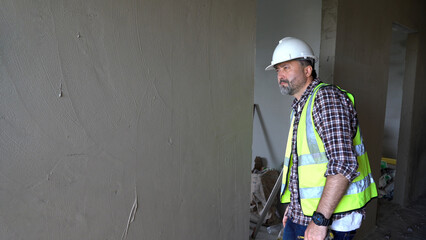 Senior architect or civil engineer inspection after plaster wall at construction site. building...