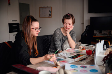 Two friends share a contemplative pause during an art-making session, exchanging ideas and enjoying the creative process together