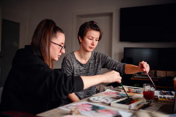 Two artists deeply focused on their watercolor techniques, a synergy of concentration and...