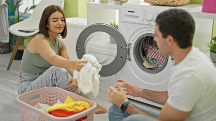 Beautiful couple smiling confident smelling clean clothes at laundry room