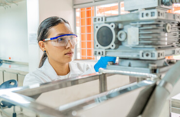 retrato de joven mujer con gafas de protección  en el laboratorio operando maquina 