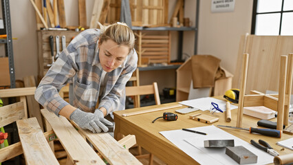 Young woman sanding wood in a well-equipped carpentry workshop, showcasing craftsmanship and...