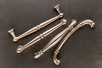 Four metal drawer handles on slate stone, furniture accessories, macro.