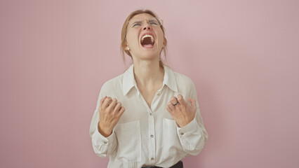 Young caucasian woman in a white shirt yelling with a frustrated expression against a pink...