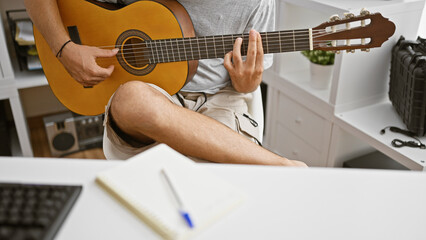 Fototapeta premium Young hispanic man playing an acoustic guitar indoors, showcasing musical talent and creativity.