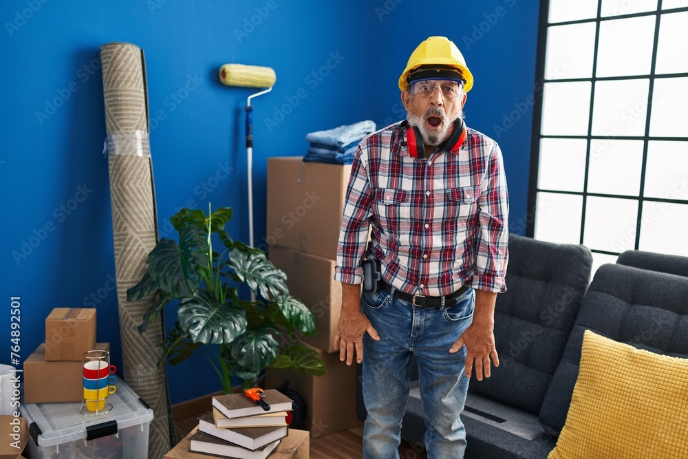 Poster Shocked senior man with grey hair dons hardhat and safety glasses, showing a scared yet excited face at his new home, eliciting an expression of pure amazement and fear! wow, amazing turnaround!