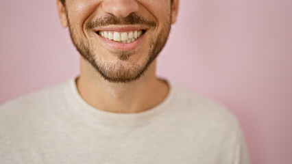 Close-up of a smiling young hispanic man with a beard against a pink background, portraying positivity and warmth.