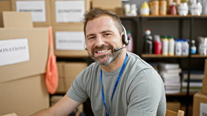 Smiling mature hispanic man with grey hair wearing a headset in a donation center warehouse