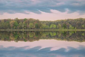 Spring landscape at dawn of the shoreline of Deep Lake with mirrored reflections in calm water, Yankee Springs State Park, Michigan, USA