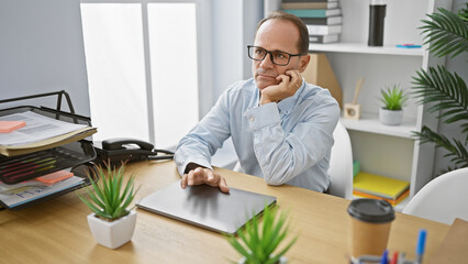 Middle age man business worker sitting on table boring at the office