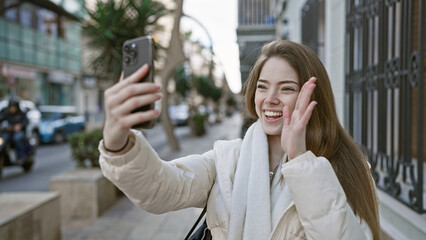 A cheerful young woman taking a selfie on a city street, highlighting urban, outdoor beauty and...