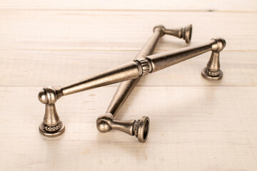 Two metal drawer handles on a wooden table, furniture accessories, macro.