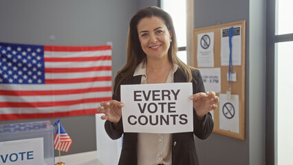 Hispanic woman holds 'every vote counts' sign in us electoral center with flag