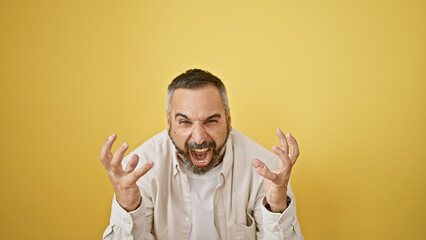 A mature man with grey beard is shouting against an isolated yellow background.