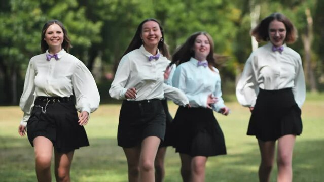 High school girls are running towards the meadow.