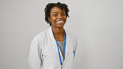 Smiling young african american woman with dreadlocks in a white lab coat over a plain background.