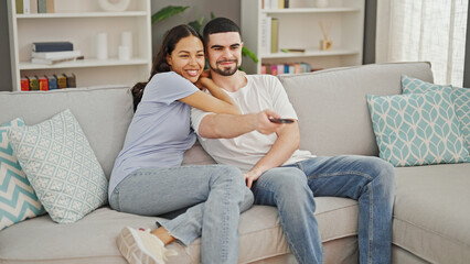 Beautiful couple finds joy in relaxing together, comfortably watching a movie, confidently...