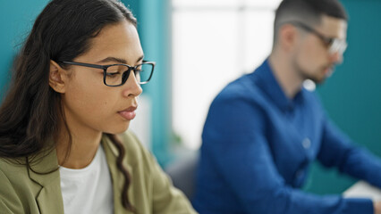 Two professional workers, man and woman, laser-focused on success, engrossed in their computer work, bonding as partners in the office interior