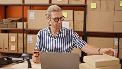 A focused man scans packages in a warehouse, surrounded by shelves and boxes, evoking a sense of...