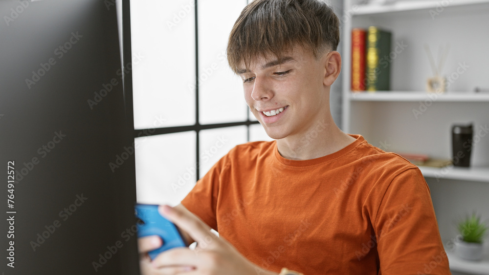 Wall mural Smiling young man studying with smartphone in a modern home setting