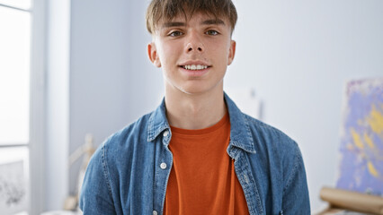 A casual blond teen boy smiling indoors for a youthful and friendly portrait.