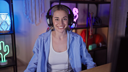 Smiling woman wearing headset in a neon-lit gaming room at night.