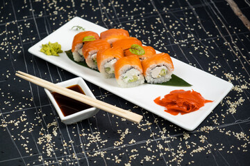 Sushi roll (Philadelphia) with salmon, smoked eel, avocado, cream cheese on black background. Sushi menu. Japanese food.