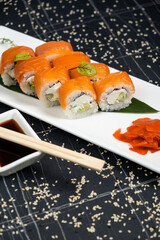 Sushi roll (Philadelphia) with salmon, smoked eel, avocado, cream cheese on black background. Sushi menu. Japanese food.