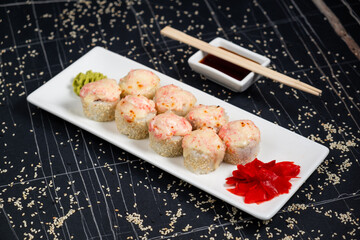 Set of baked sushi rolls with wasabi and ginger on a black background. Japanese oriental cuisine