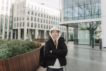 Fototapeta premium Tourist teenage girl traveling alone through the city streets in the autumn-winter season. Modern solo travel, lone traveler, Winter vacation railroad adventure concept.