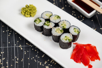 Top view on classic tasty vegetarian kappa maki sushi rolls with fresh cucumbers and rice wrapped in nori on dark background