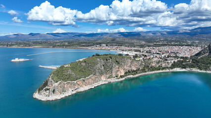 Naklejka premium Aerial drone photo of iconic Acronafplia fortress overlooking old city of Nafplio below famous castle of Palamidi as seen in a spring morning with beautiful clouds and deep blue sky, Argolida, Greece