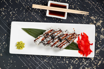 Set of sushi rolls dragon on a black matte plate. Japanese traditional sushi dish with avocado, eel and soy sauce. A beautiful dish for an Asian restaurant menu.