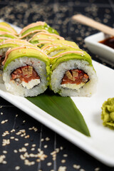 Green dragon sushi roll with eel, avocado, cucumber and ginger, accompanied with fried tempura shrimp. Traditional asian rice sushi healthy seafood
